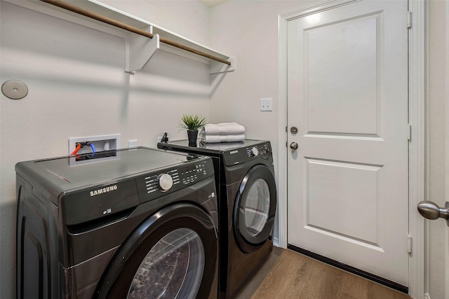 laundry room with washer and dryer and wood-type flooring