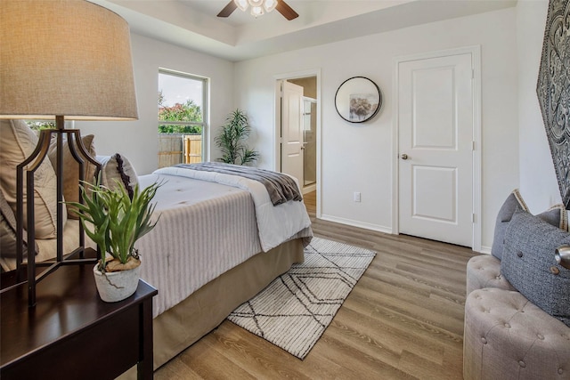 bedroom with ceiling fan, light wood-type flooring, and ensuite bath