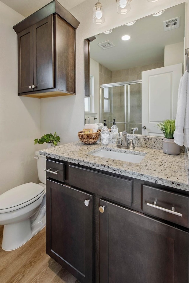 bathroom featuring vanity, hardwood / wood-style flooring, toilet, and an enclosed shower