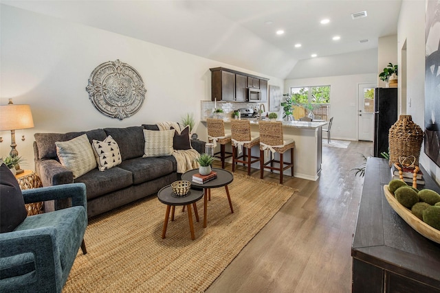 living room featuring light hardwood / wood-style flooring and vaulted ceiling