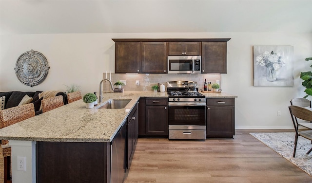 kitchen with sink, stainless steel appliances, tasteful backsplash, and light hardwood / wood-style flooring