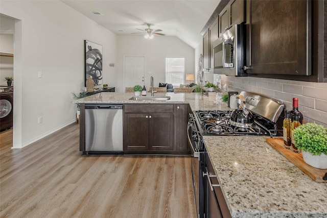 kitchen with light stone counters, dark brown cabinetry, stainless steel appliances, sink, and light hardwood / wood-style floors