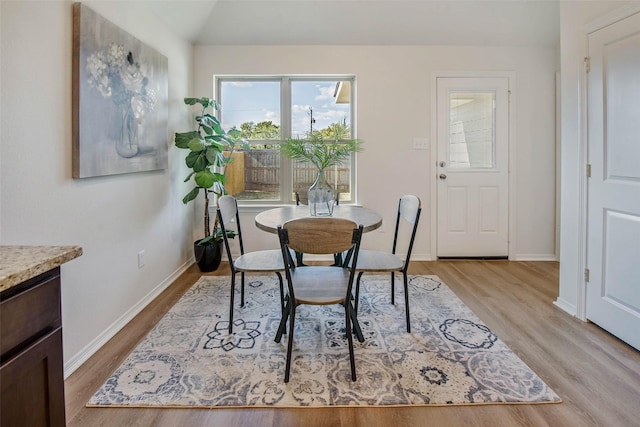 dining space with light hardwood / wood-style floors and vaulted ceiling