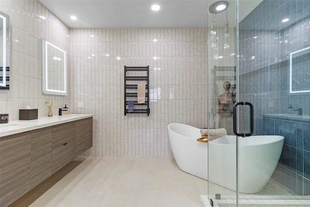 bathroom with plus walk in shower, tile patterned flooring, tile walls, and vanity