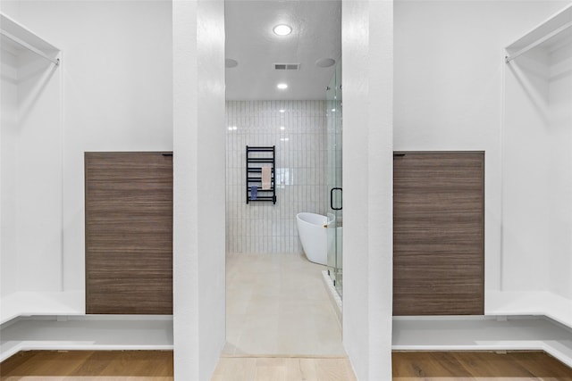 bathroom with tile walls, independent shower and bath, and hardwood / wood-style floors