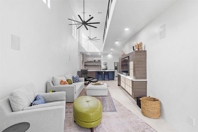 living room with ceiling fan and a towering ceiling