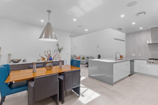 kitchen with pendant lighting, sink, white cabinetry, stainless steel gas cooktop, and wall chimney exhaust hood