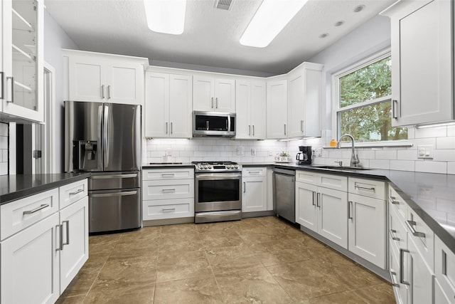 kitchen with decorative backsplash, stainless steel appliances, white cabinetry, and sink