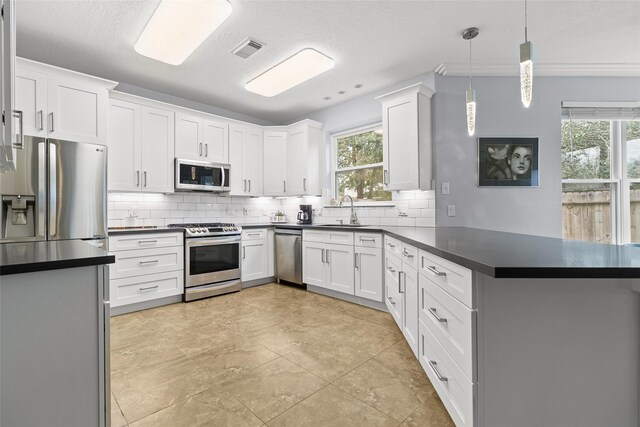 kitchen with white cabinets, appliances with stainless steel finishes, sink, and pendant lighting