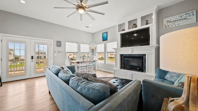 living room with ceiling fan, a fireplace, a healthy amount of sunlight, and light wood-type flooring