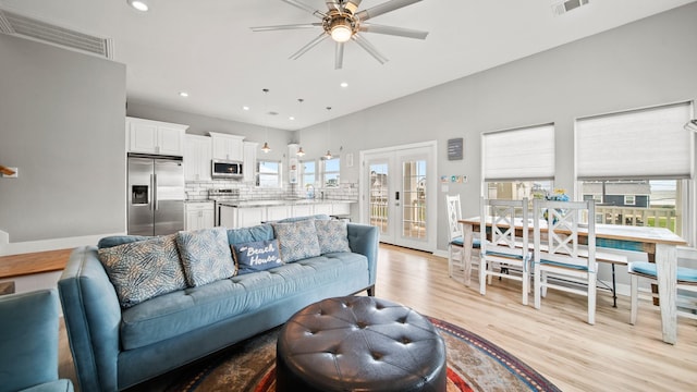 living room featuring ceiling fan, french doors, and light wood-type flooring