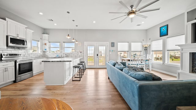 living room with a wealth of natural light, sink, ceiling fan, and light hardwood / wood-style floors