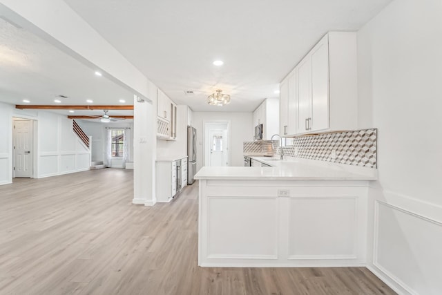 kitchen featuring white cabinets, sink, light hardwood / wood-style floors, kitchen peninsula, and stainless steel appliances