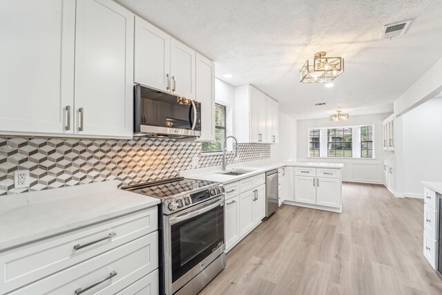 kitchen featuring decorative backsplash, stainless steel appliances, white cabinetry, and light hardwood / wood-style flooring