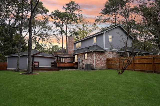 back house at dusk with a yard, a deck, and central air condition unit