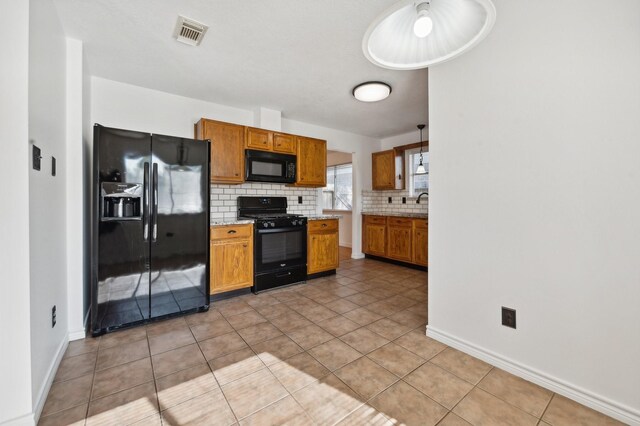 kitchen featuring backsplash, pendant lighting, light tile patterned floors, and black appliances