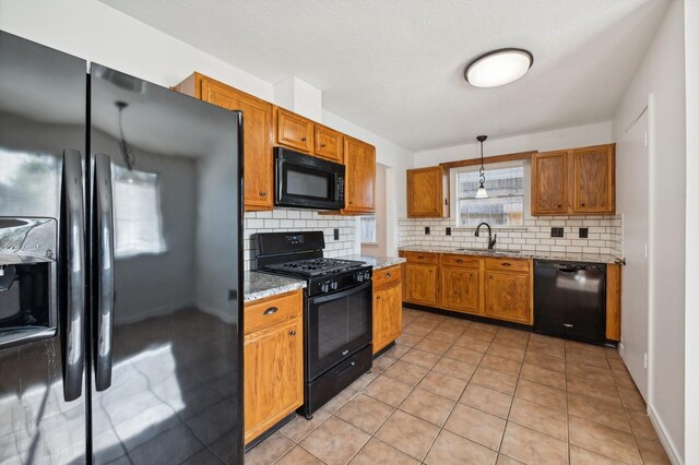 kitchen featuring black appliances, pendant lighting, sink, and tasteful backsplash