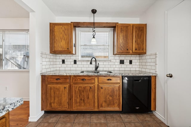 kitchen with dishwasher, sink, light stone counters, backsplash, and decorative light fixtures