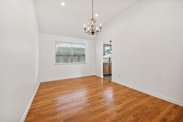 spare room featuring hardwood / wood-style floors, a notable chandelier, sink, and high vaulted ceiling