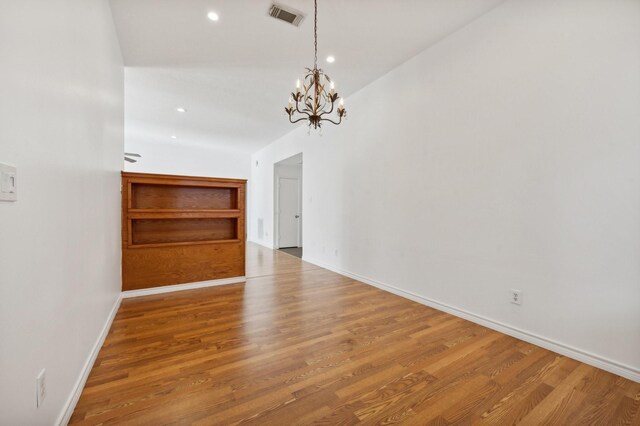 unfurnished dining area featuring wood-type flooring and a notable chandelier