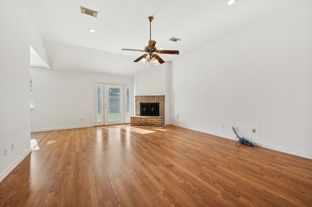 unfurnished living room with ceiling fan, lofted ceiling, a fireplace, and light hardwood / wood-style flooring