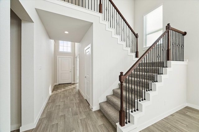 staircase featuring hardwood / wood-style floors, plenty of natural light, and a high ceiling