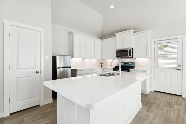 kitchen featuring white cabinetry, an island with sink, lofted ceiling, and appliances with stainless steel finishes