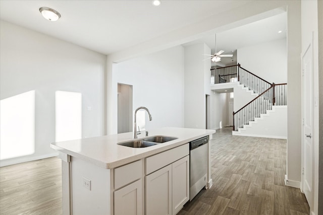 kitchen featuring dishwasher, a kitchen island with sink, white cabinets, sink, and light hardwood / wood-style flooring