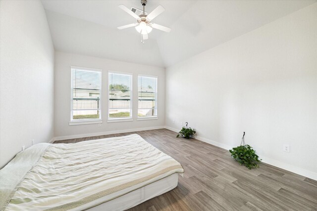 bedroom with light hardwood / wood-style flooring, vaulted ceiling, and ceiling fan