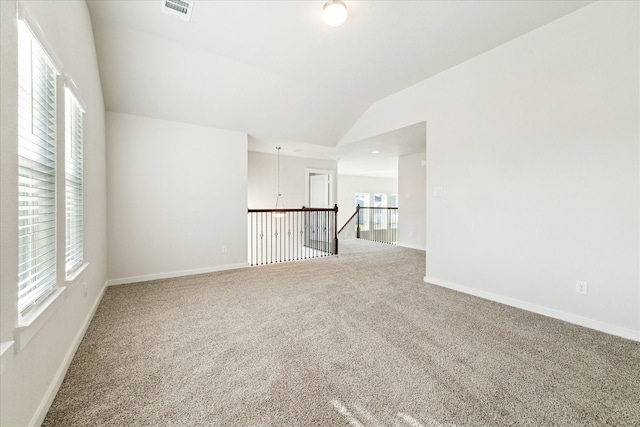 carpeted empty room with plenty of natural light and lofted ceiling