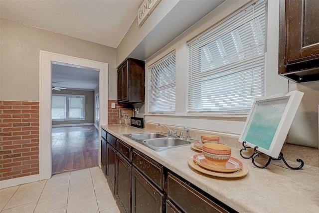 kitchen with light tile patterned flooring, dark brown cabinets, ceiling fan, and sink