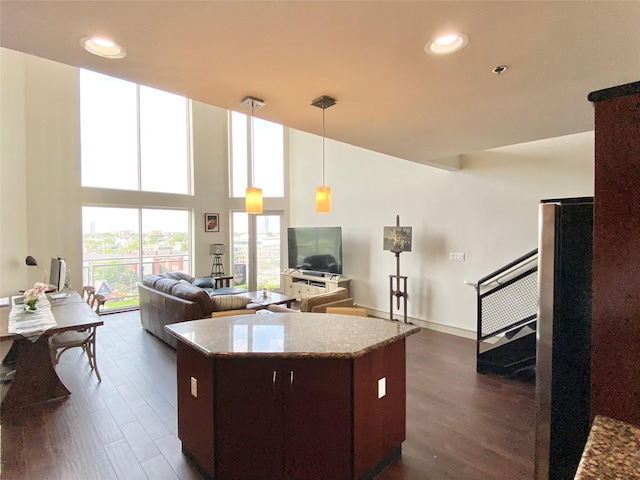 kitchen featuring dark wood-style floors, freestanding refrigerator, a high ceiling, and a center island