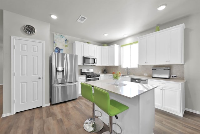 kitchen with a center island, dark hardwood / wood-style flooring, white cabinetry, and stainless steel appliances