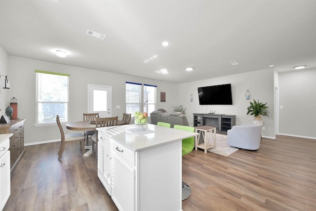 kitchen with white cabinets, plenty of natural light, a center island, and light hardwood / wood-style flooring