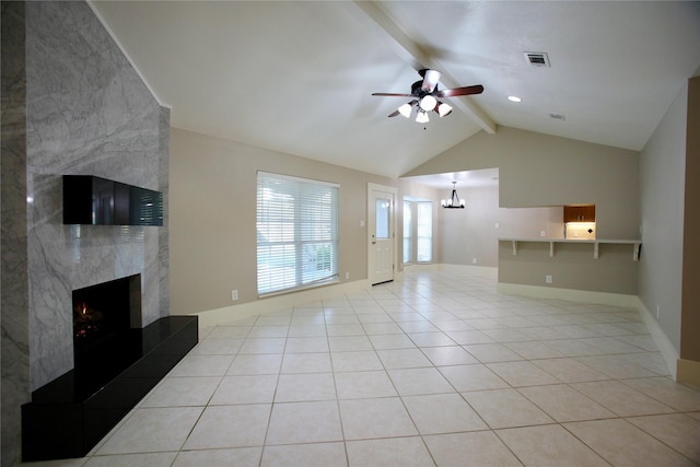 unfurnished living room with a fireplace, light tile patterned flooring, lofted ceiling with beams, and ceiling fan with notable chandelier