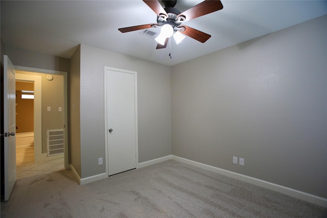 unfurnished bedroom with ceiling fan, light carpet, and a closet