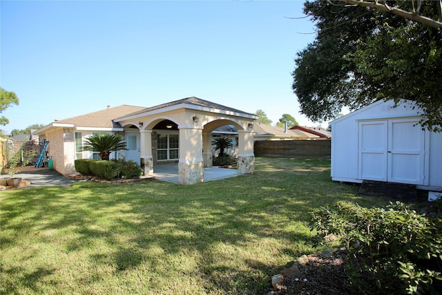 back of property with a yard, a storage unit, and a patio area