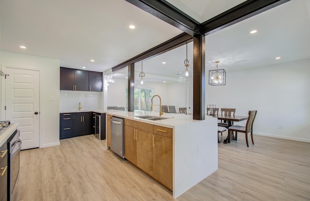 kitchen featuring pendant lighting, light hardwood / wood-style floors, sink, and an island with sink