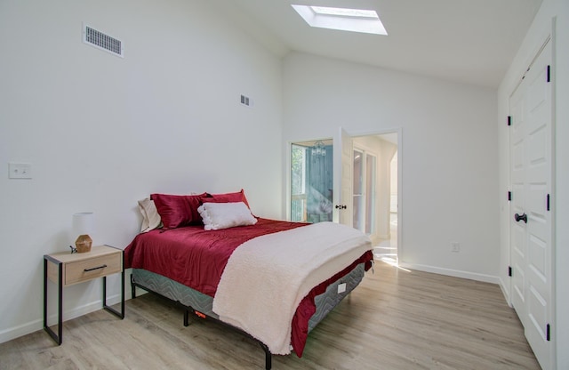 bedroom featuring light wood-type flooring, high vaulted ceiling, and connected bathroom