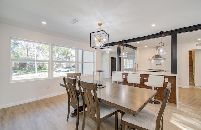 dining room featuring a chandelier, sink, and light hardwood / wood-style floors