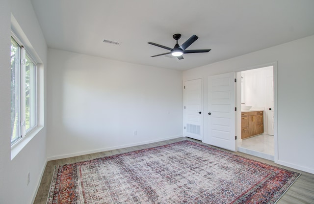 unfurnished bedroom featuring connected bathroom, ceiling fan, and light hardwood / wood-style flooring