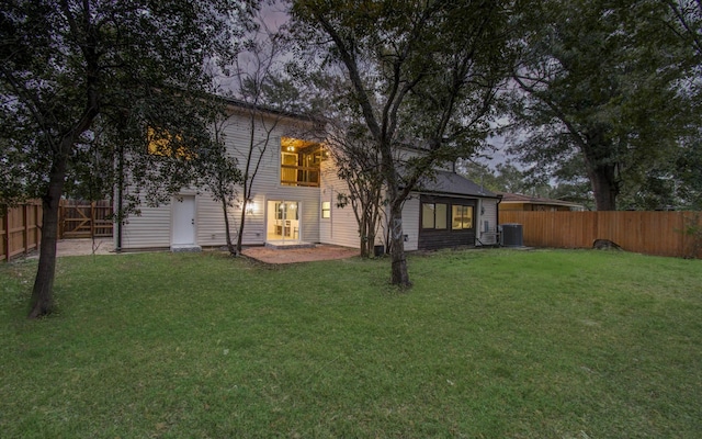 back of house featuring central air condition unit and a yard