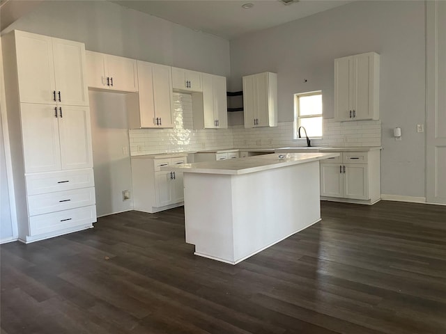 kitchen with dark hardwood / wood-style floors, a center island, white cabinetry, and sink