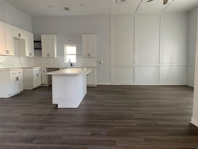 kitchen featuring dark hardwood / wood-style flooring, white cabinetry, a kitchen island, and ceiling fan