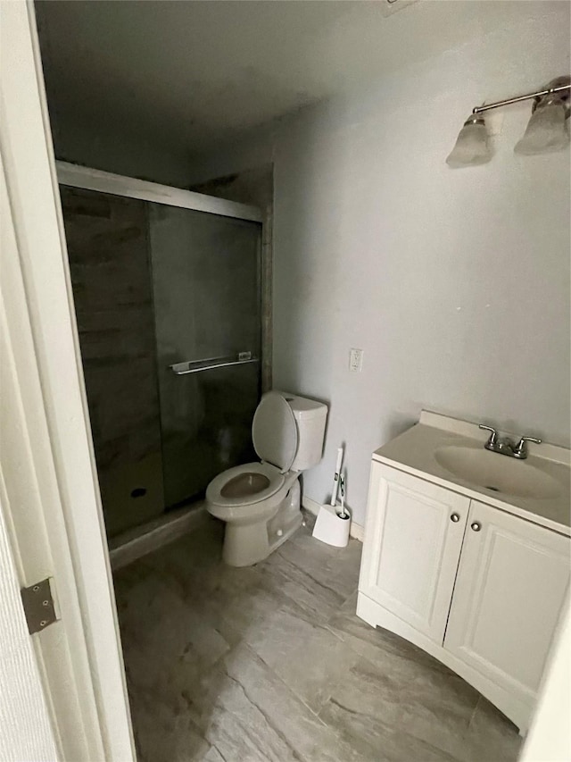 bathroom featuring vanity, toilet, and a shower with shower door