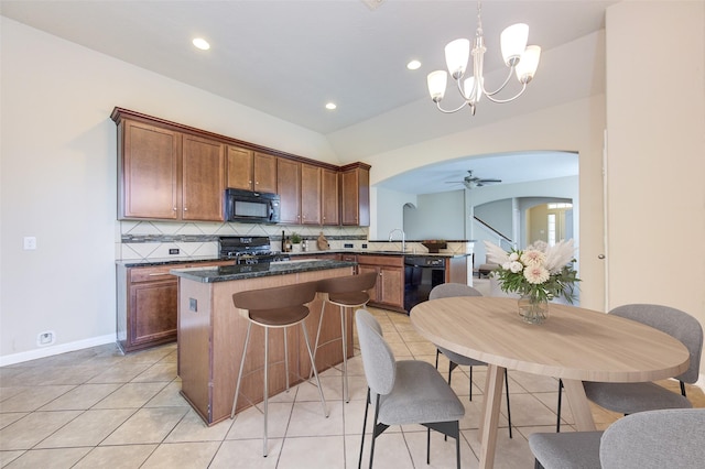 kitchen with tasteful backsplash, kitchen peninsula, pendant lighting, black appliances, and ceiling fan with notable chandelier