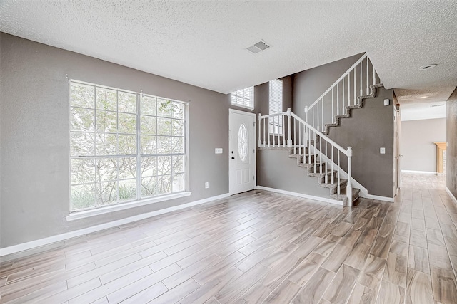 entryway with a textured ceiling and light wood-type flooring