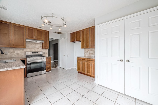 kitchen featuring a textured ceiling, sink, tasteful backsplash, and stainless steel range oven