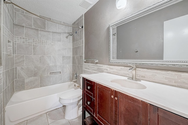 full bathroom with tile patterned floors, vanity, a textured ceiling, tiled shower / bath combo, and toilet