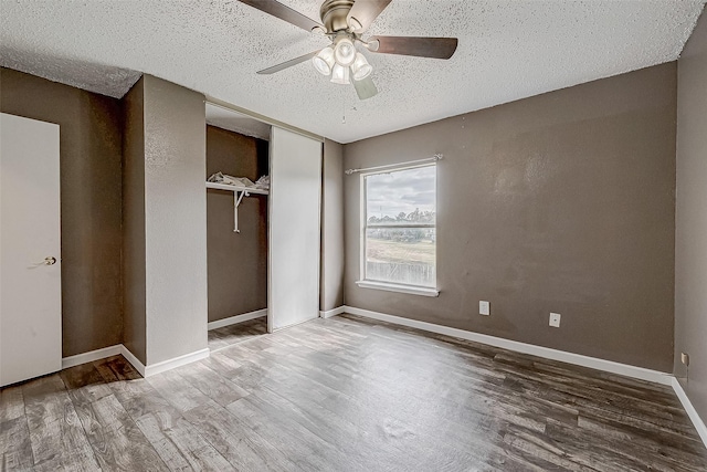 unfurnished bedroom featuring hardwood / wood-style flooring, ceiling fan, a textured ceiling, and a closet